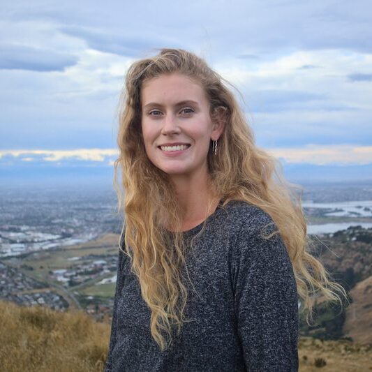 Headshot of Sara, with panoramic views of Lyttelton, NZ in the background.